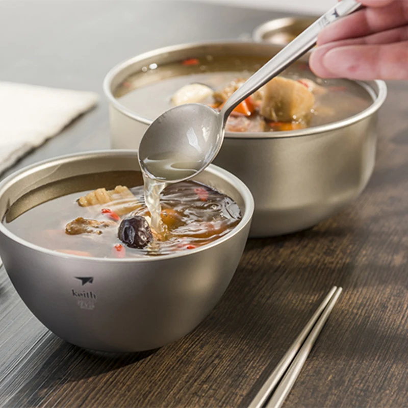 Pouring soup into stainless steel bowl with spoon.