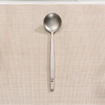 Stainless steel soup spoon on woven placemat.