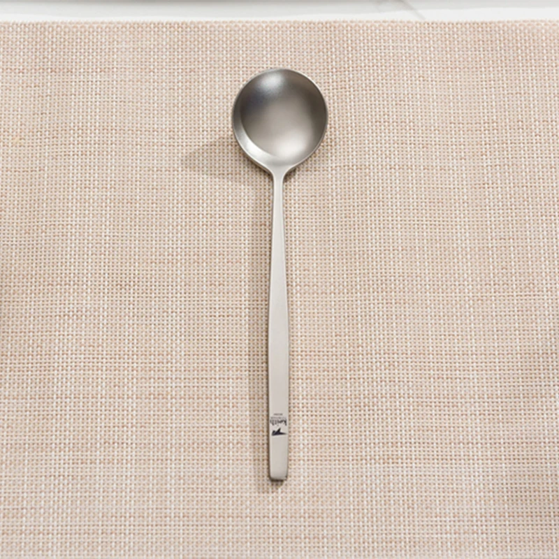 Stainless steel soup spoon on woven placemat.